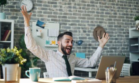 a man sitting at a desk with his arms in the air